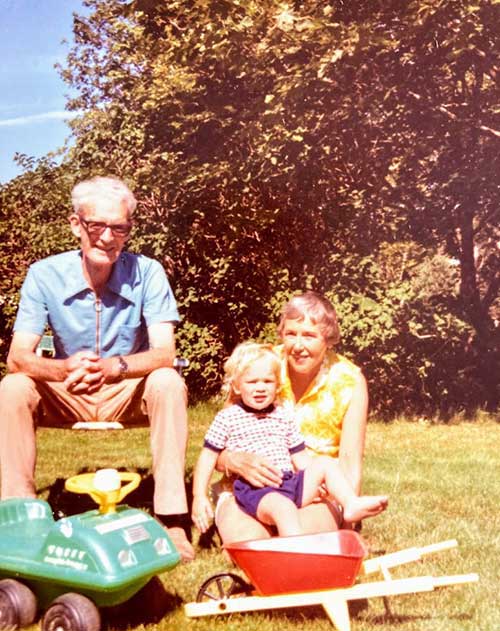 An elderly couple sit holding a baby.