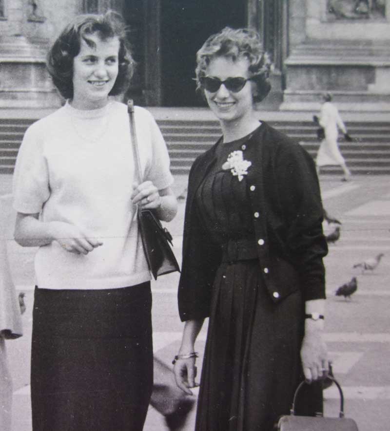 Two women stand in front of an old building.
