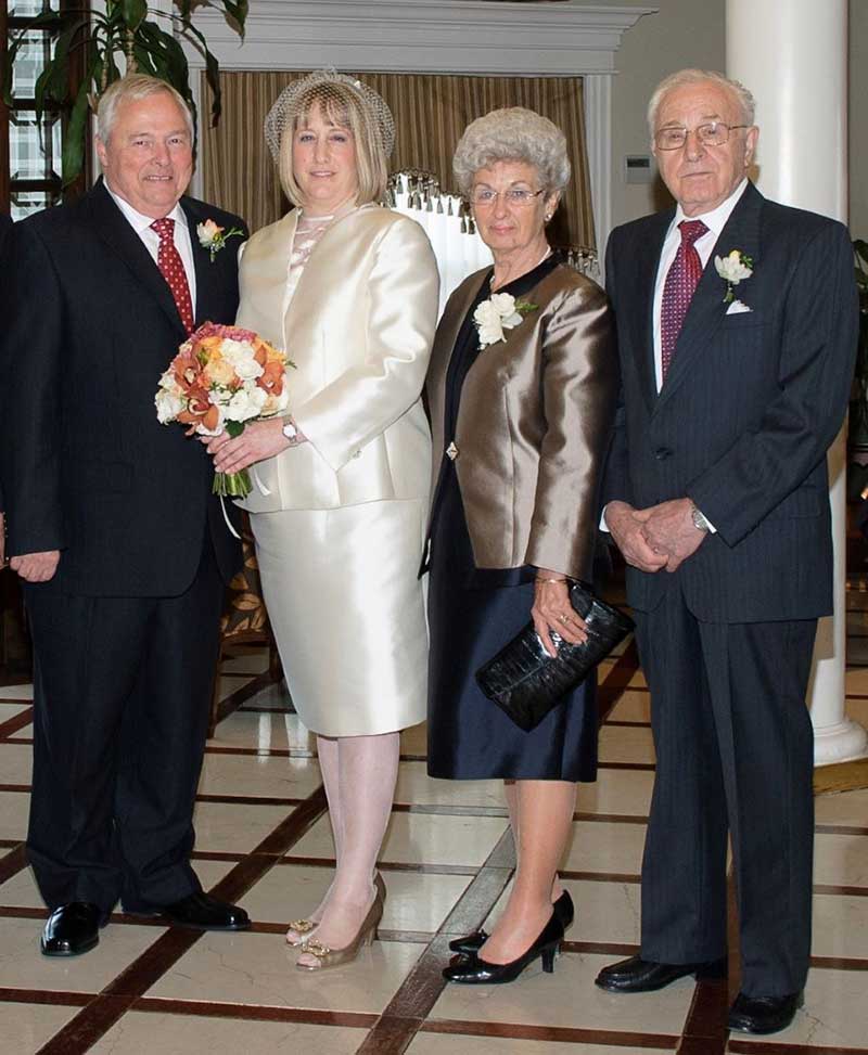 Four well-dressed adults in formal wear stand together as they pose for the camera.