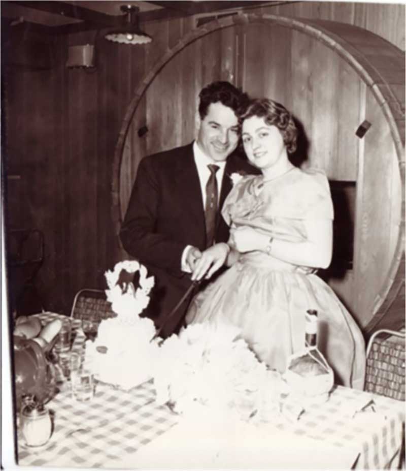 A newlywed couple cutting the cake on their wedding day.