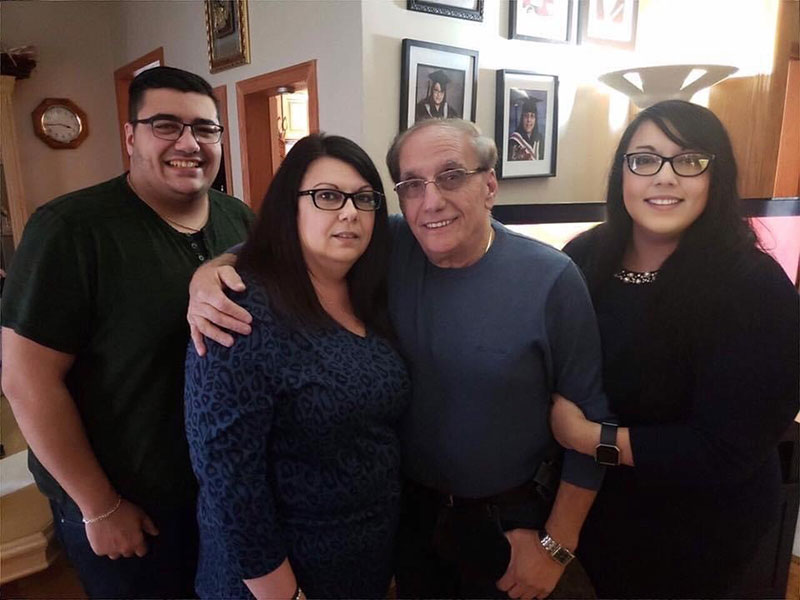 Young man and woman stand on either side of their parents.