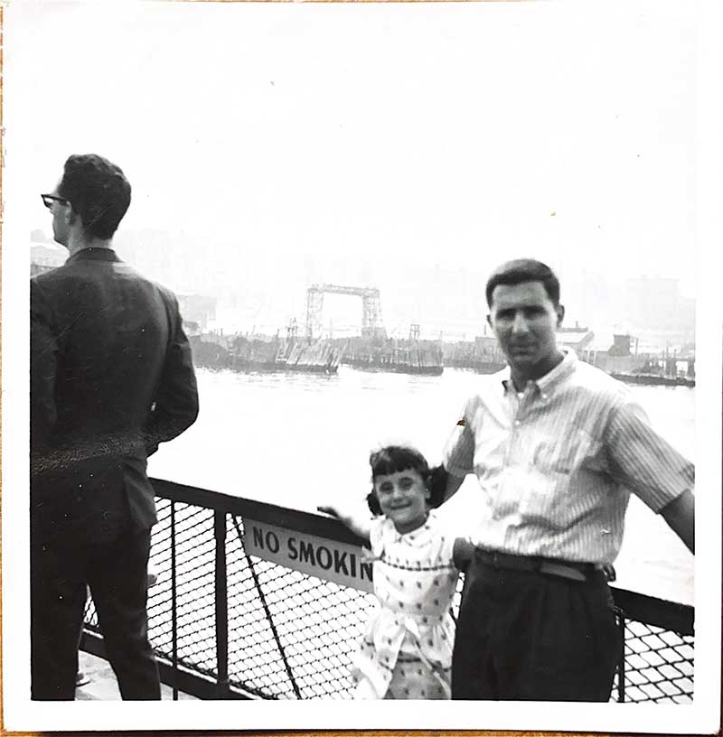A man and young girl stand against a railing with a sign that says No Smoking.