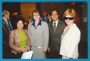 Om standing with three other people in large room.