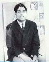 Om in suit and tie, sitting atop table. Photo is cracked and has piece of tape on it.