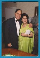 Man in suit and bowtie hugging woman in beautiful green sari.