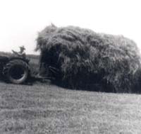 Farmer on tractor pulling lots of hay.