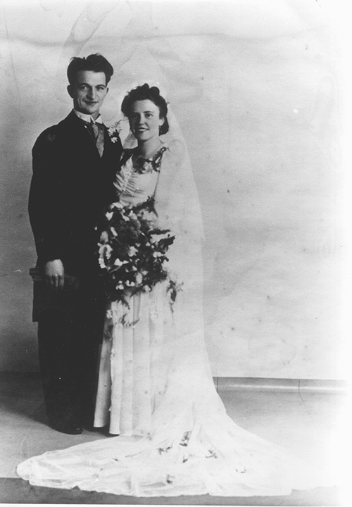 Newly married couple pose for photo while holding flowers.