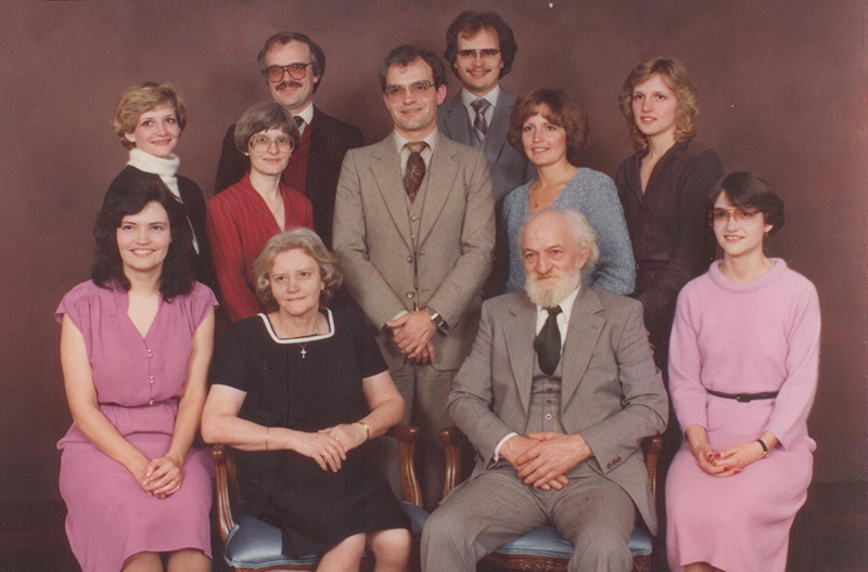 Well-dressed family members sitting and standing for group photo.