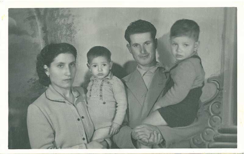 A beautiful couple holding kids standing for photo.