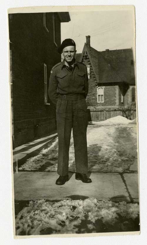 A man stands in military clothing with his hands behind his back.