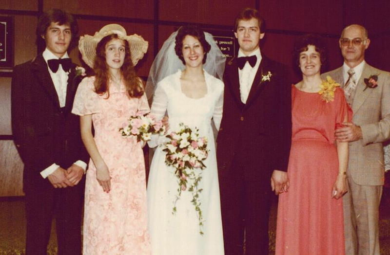 A beautiful bride in a wedding dress with her family surrounding her.