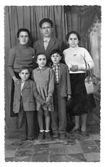 Photograph of three adults and three children posing in front of a curtained area.