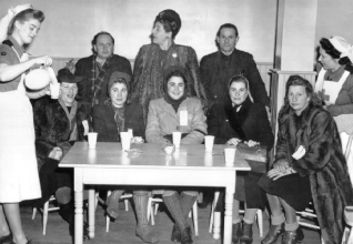 Several people sitting around a table having drinks served.
