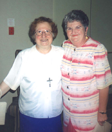 Older sister Liota standing with another woman in a striped dress.