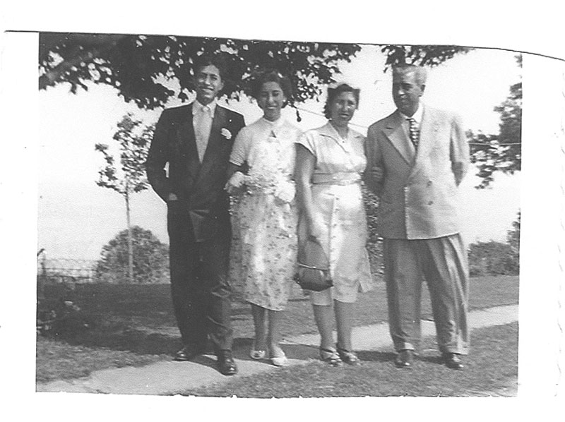 Two well-dressed couples stand together and smile for the camera.
