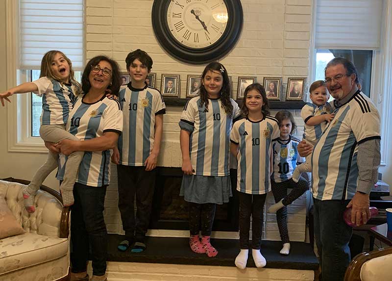 Several family members of different ages are standing and wearing identical sports jerseys.