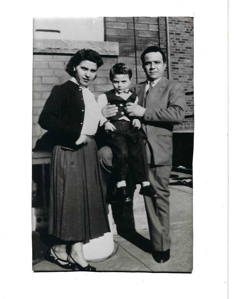 Young boy in between mother and father, all well-dressed.