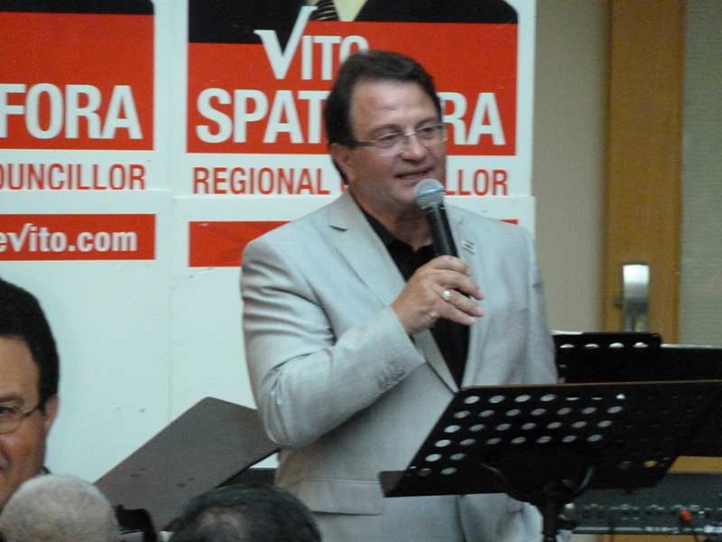A man stands with a microphone at a political rally.