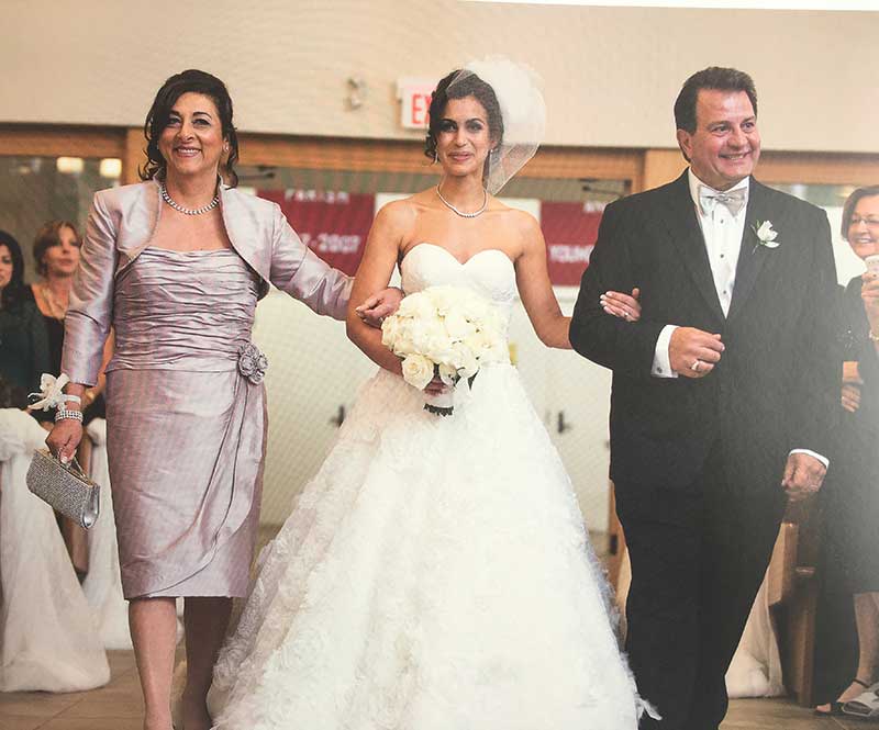 A bride is being escorted by her mother and father.
