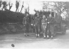 Group of soldiers standing in front of army jeep.