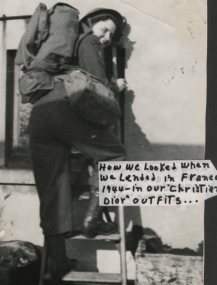 Young woman with a backpack, climbing a ladder and looking at the camera over her shoulder.