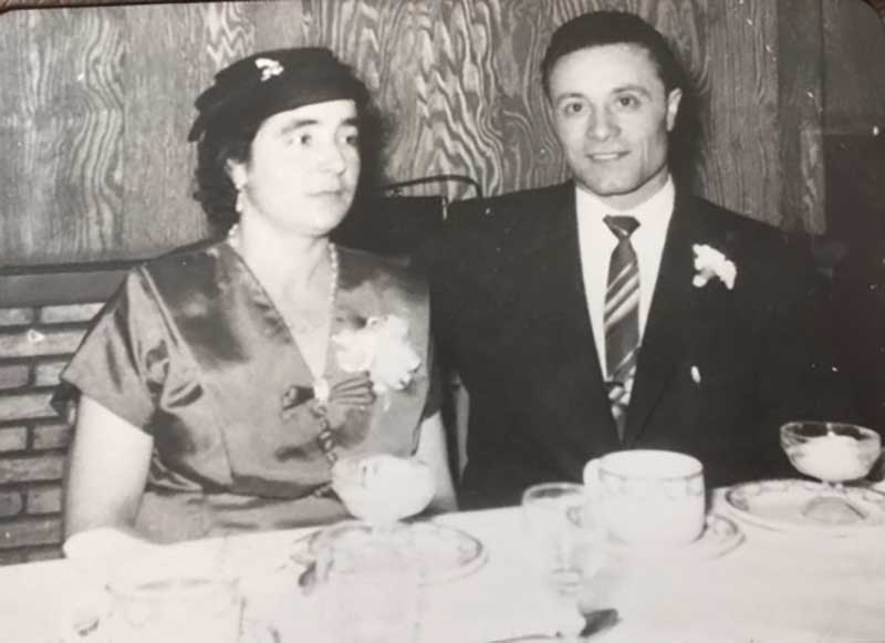 Well-dressed couple seated at a dinner table.