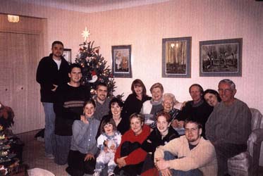 Several family members sitting around the living room couch during the holidays.