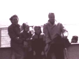 A mother, a father and their two children leaning against the railing of the boat.