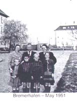 Seven family members posing on the sidewalk in front of a building.