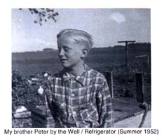 Young blond boy in checkered shirt, standing in front of a well.