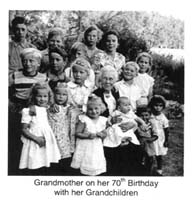 Grandmother seated surrounded by sixteen grandchildren.