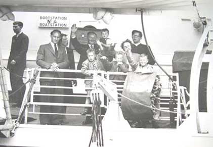 Young men and children standing on a ship and waving.