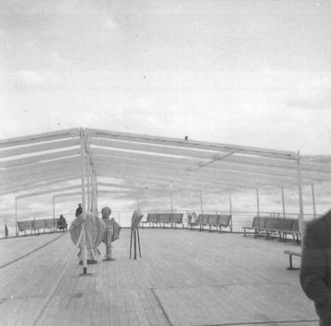 Few people are sitting on the upper deck of the ship.