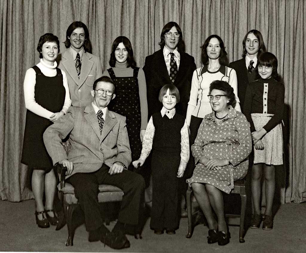 A black and white family portrait with parents seated and children standing behind them.