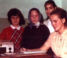 Colour photograph showing four young girls sitting on a couch.