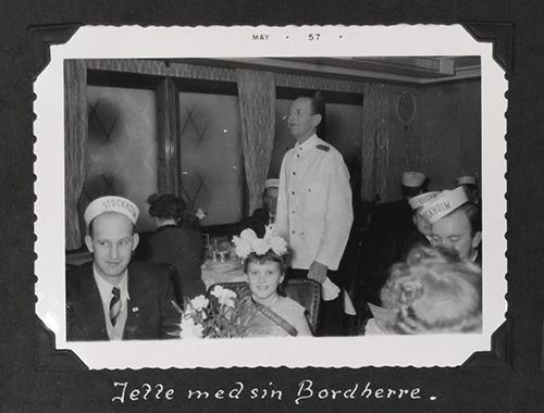 Little beautiful girl sitting with handsome man wearing a cap, and waiter standing behind them.