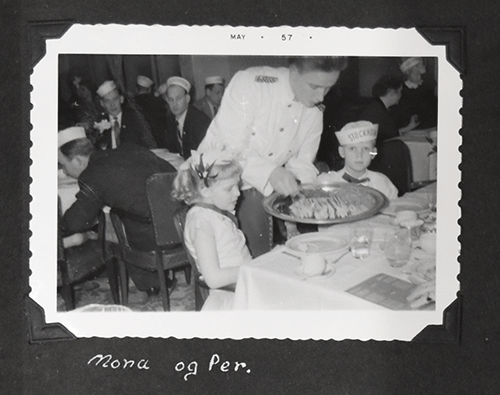 Two kids are sitting and waiter is serving food to them.