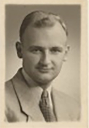 A young man in suit and tie gazes directly into the camera.