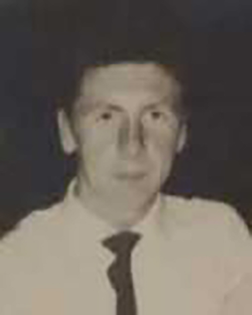 Young man in a white shirt and tie looks pensively at the camera.