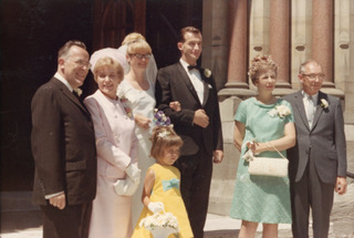 A bride and groom surrounded two couples and a flower girl in front of them.
